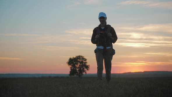 Young Hiker Woman with a Backpack at Sunset