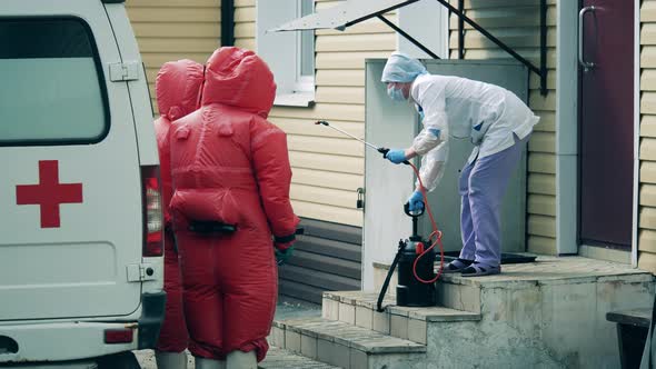 Nurse with a Disinfectant and Medical Staff in Red Suits