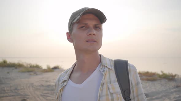 Portrait of Young Attractive Guy Looking for Friends and Place for Picnic on Sunny Evening Beach