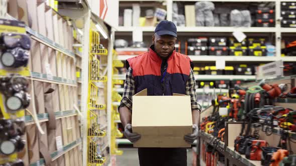 Worker in Hardware Store Carrying Box