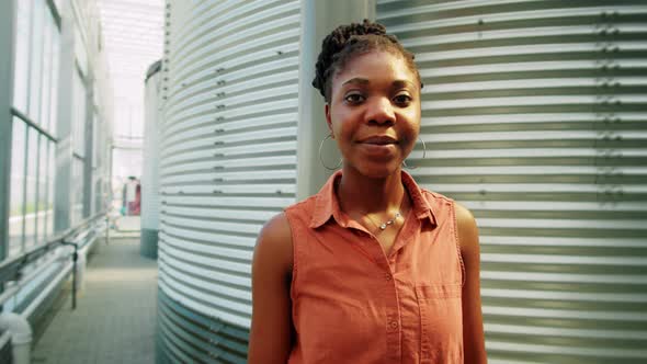 Portrait of African American Woman by Water Storage Tank in Greenhouse