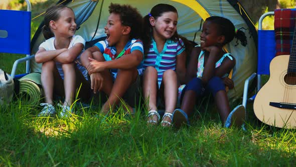 Kids sitting outside tent at campsite