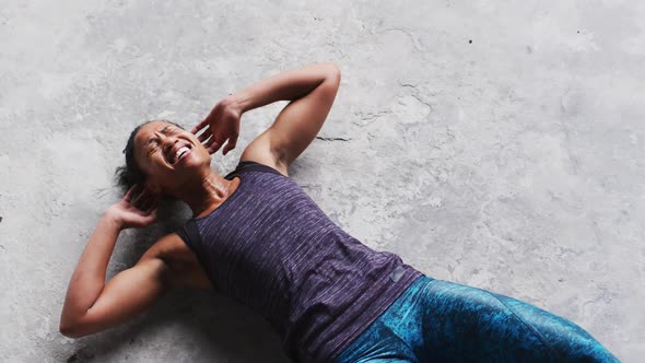 African american woman doing crunches on the floor in an empty urban building
