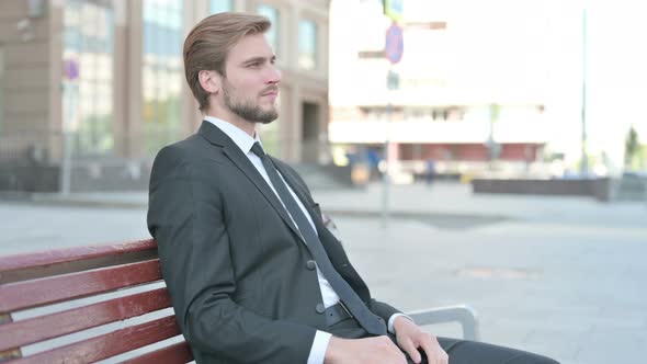 Young Businessman Smiling at Camera While Sitting on Bench