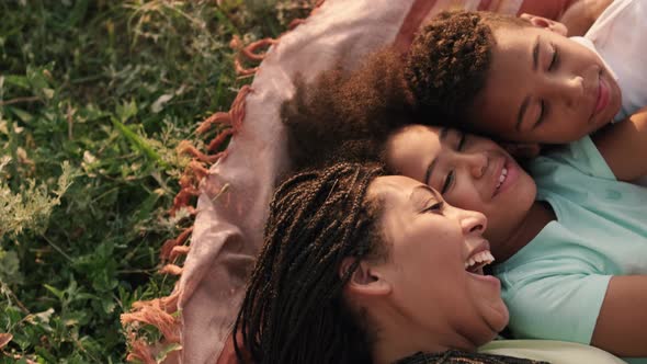 A smiling afro-american family mother and her children lay down on the plaid