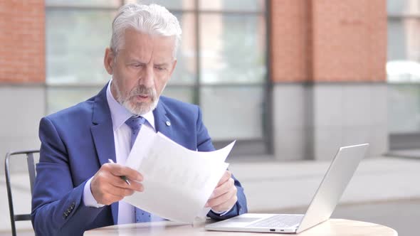 Old Businessman Upset While Reading Documents Outdoor