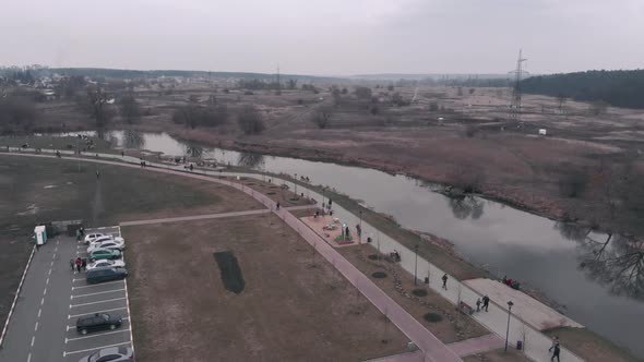 Pedestrian recreation area with river and car parking from birds eye view.