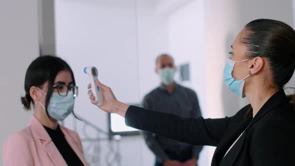 Business Woman with Face Mask Checking Collegues Forehead Temperature