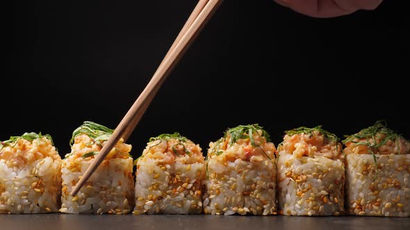 Take One Sushi Roll From Black Slate Board Using Chopsticks