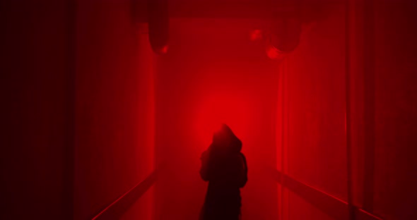 Boxer boxing with a shadow in a semi-dark corridor with a red illumination behind his back