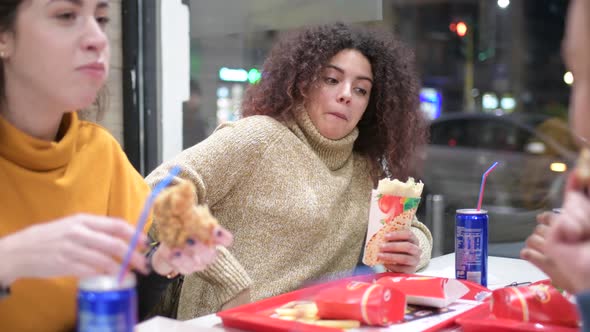 young women multiethnic indoor eating at fast food