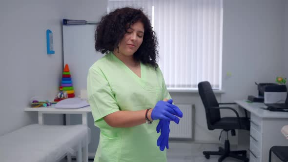 Intelligent Confident Doctor Posing Putting on Surgical Gloves Standing in Hospital Indoors