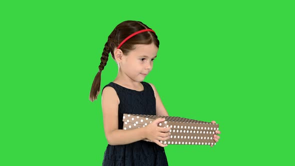 Little Girl in Black Dress Walking with a Gift Box in Her Hands on a Green Screen Chroma Key