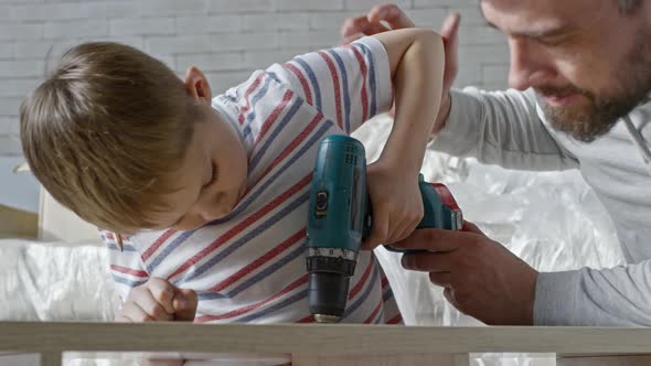 Father Teaching Son to Drive Screws into Furniture alt