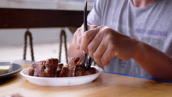 Male Hands Cutting with a Knife and Fork Juicy Fried Steak Meat in Summer Cafe