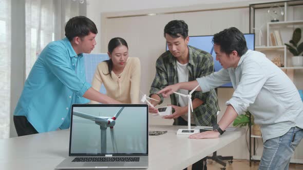 Laptop Showing The Video Of Wind Turbine While Asian Engineers Group Discussing About Work