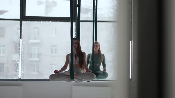 Two Young Women Swing on Hammocks and Meditate Concentrating on Their Breath