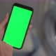 Woman Holds a Mobile Phone with a Green Chromakey Screen in Her Hands in Laundry - VideoHive Item for Sale
