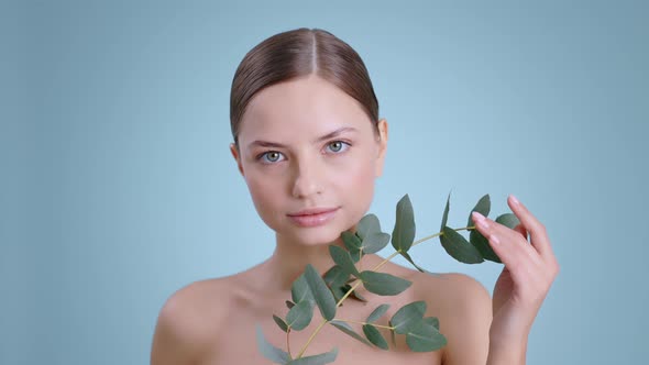 Portrait of Seductive Young Woman Holding Plant Branch While Looking to Camera 