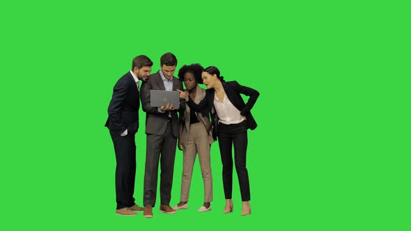 Young Colleagues in Suits Discussing a Project Looking at the Screen of the Laptop on a Green Screen