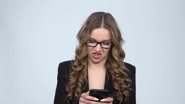 Dissatisfied Businesswoman Texting on Her Phone on Gray Background in Studio, Slow Motion