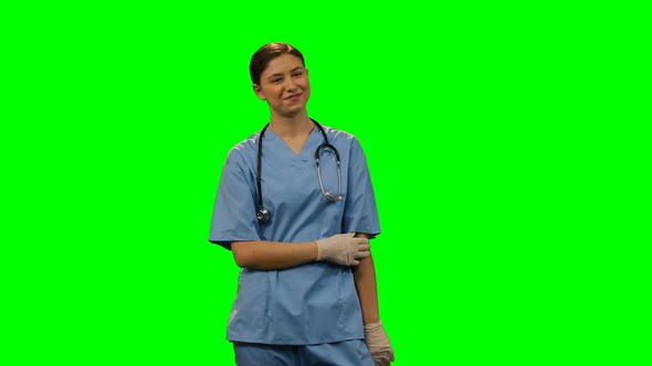 Happy female surgeon standing against green screen