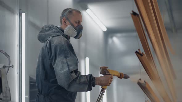 A Man in a Respirator is Painting Metal with a Powder Method