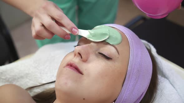 Woman getting facial mask in spa. Young woman in the mask cosmetic procedure in spa salon