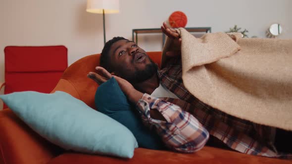 Terrified Scared African American Young Man Wakes Up From Stress Nightmare in Bedroom at Home Sofa