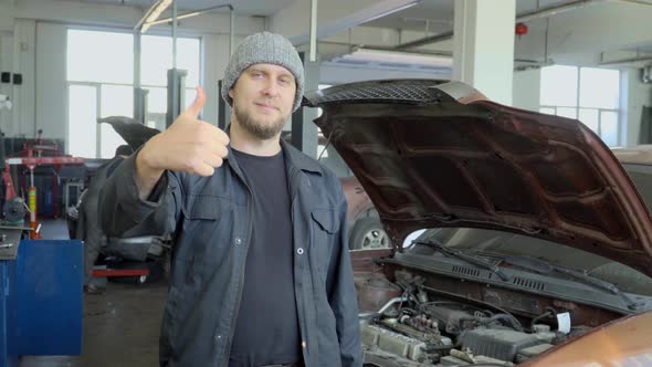 Mechanic in car repair shop showing thumbs up