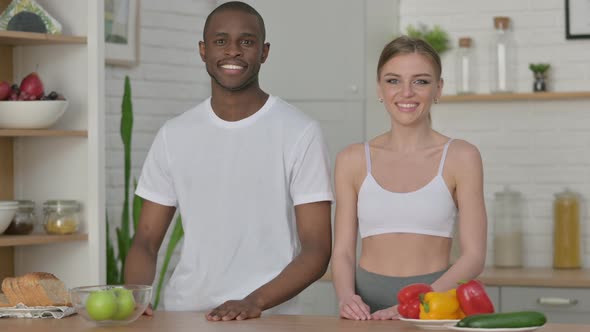 Athletic Young Woman and African Man Smiling at Camera in Kitchen