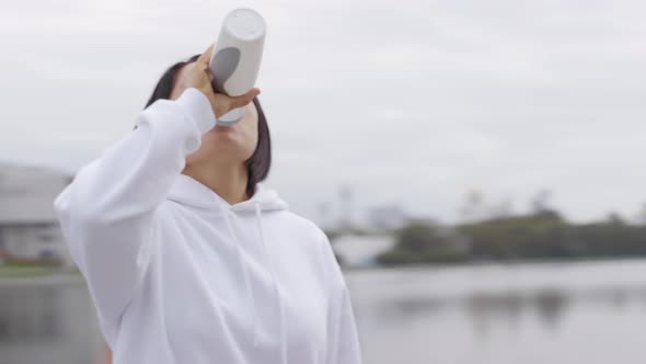 Mid-Aged Asian Woman Drinking Water after Running Outoors