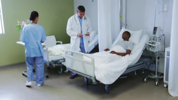 Front view of Caucasian male doctor talking with patient in ward at hospital