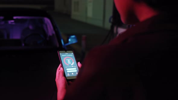 Woman Using App While Charging Car at EV Station