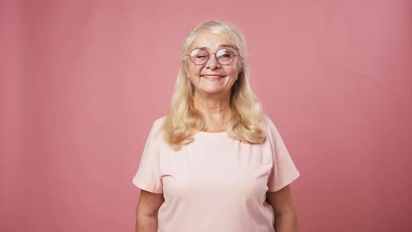 Positive Senior Lady in Glasses Showing Okay Gesture Pink Studio Background