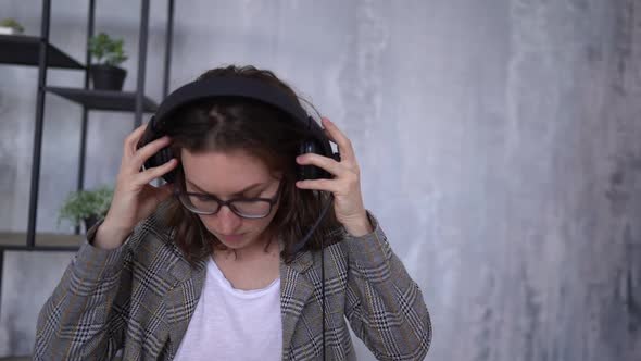 Young Woman Puts on Headphones and Prepares for a Video Call While Sitting in the Office Near a