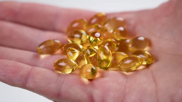 Yellow softgels capsules Omega-3. Handful of fish oil pills in hand. Natural supplement