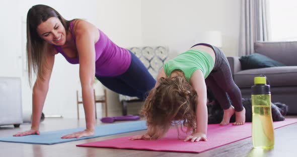 Caucasian mother and daughter practising yoga in living room