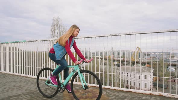 A Young Hipster Girl Riding a Fixed Gear Bike at City Centre Slow Motion