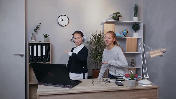 Joyful Two Teen Girls which Making Dancing Movements which Showing on Computer Screen