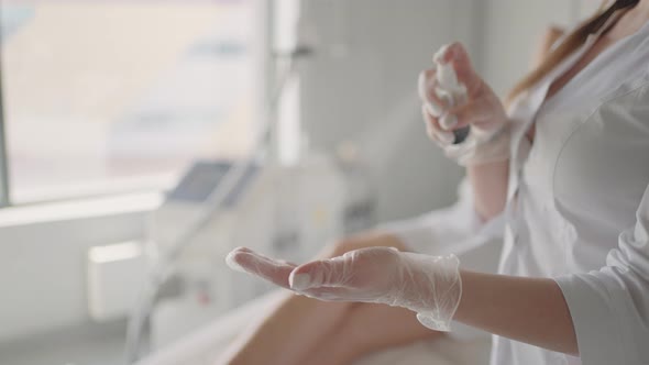 Cosmetologist or Physician Therapist Woman is Spraying Disinfectant on Hands in Gloves Before