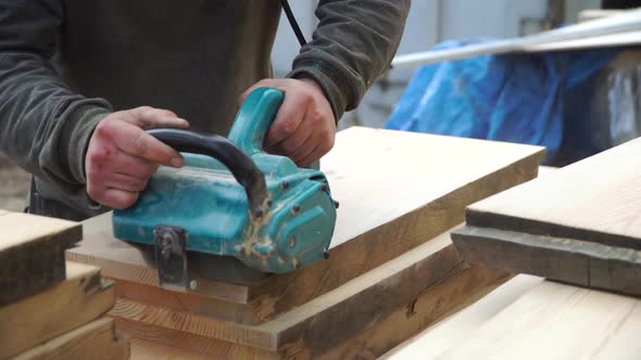 Working Man Is Polishing a Piece of Wood with a Machine for Grinding in the Hands