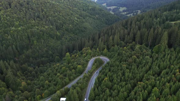 Aerial tilt down over mountain road hairpin turn over Nyerges Teto, Romania