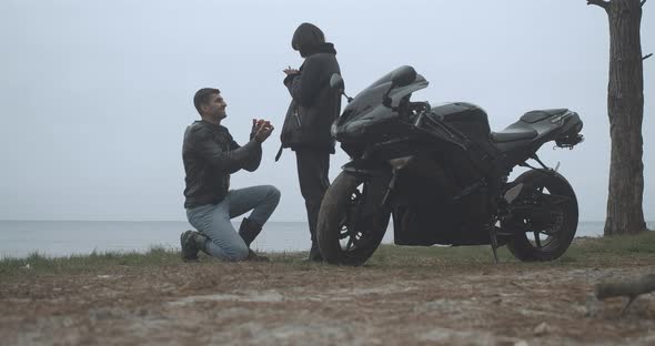 Wide Shot of Happy Boyfriend Proposing To Girlfriend on Cloudy River Bank Outdoors. Happy