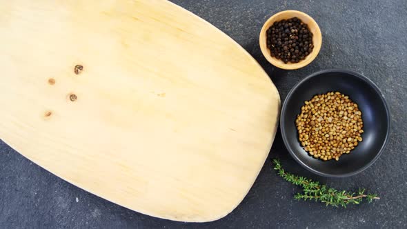 Coriander seeds, black pepper, rosemary herbs and wooden board