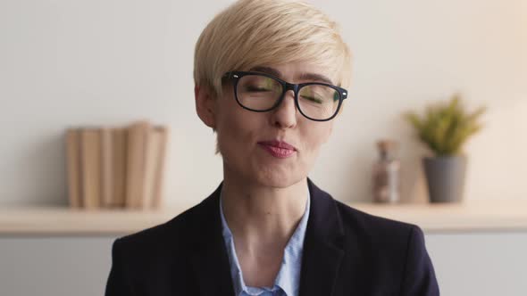 Close Up Portrait of Positive Mature Woman Coach Wearing Eyeglasses Talking to Camera Sitting at