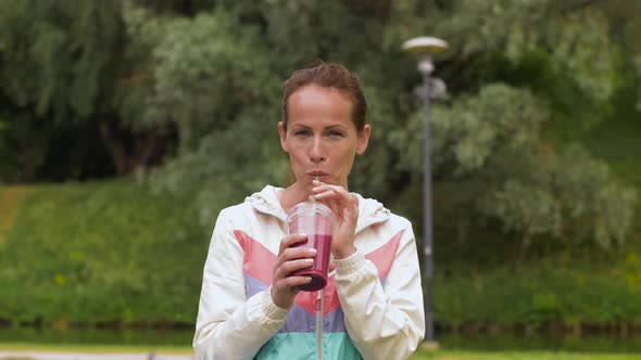 Woman Drinking Smoothie After Exercising in Park 