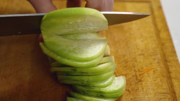 Closeup of a Cook Slicing Green Radishes on a Kitchen Board