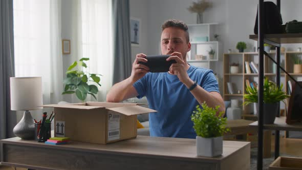 A Handsome Young Man Pulls Out a Portable Speaker From a Cardboard Box