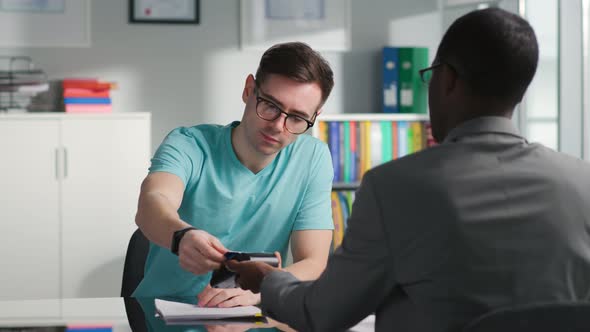 Young Man Having Meeting with Auto Dealer and Pay Deposit with Credit Card